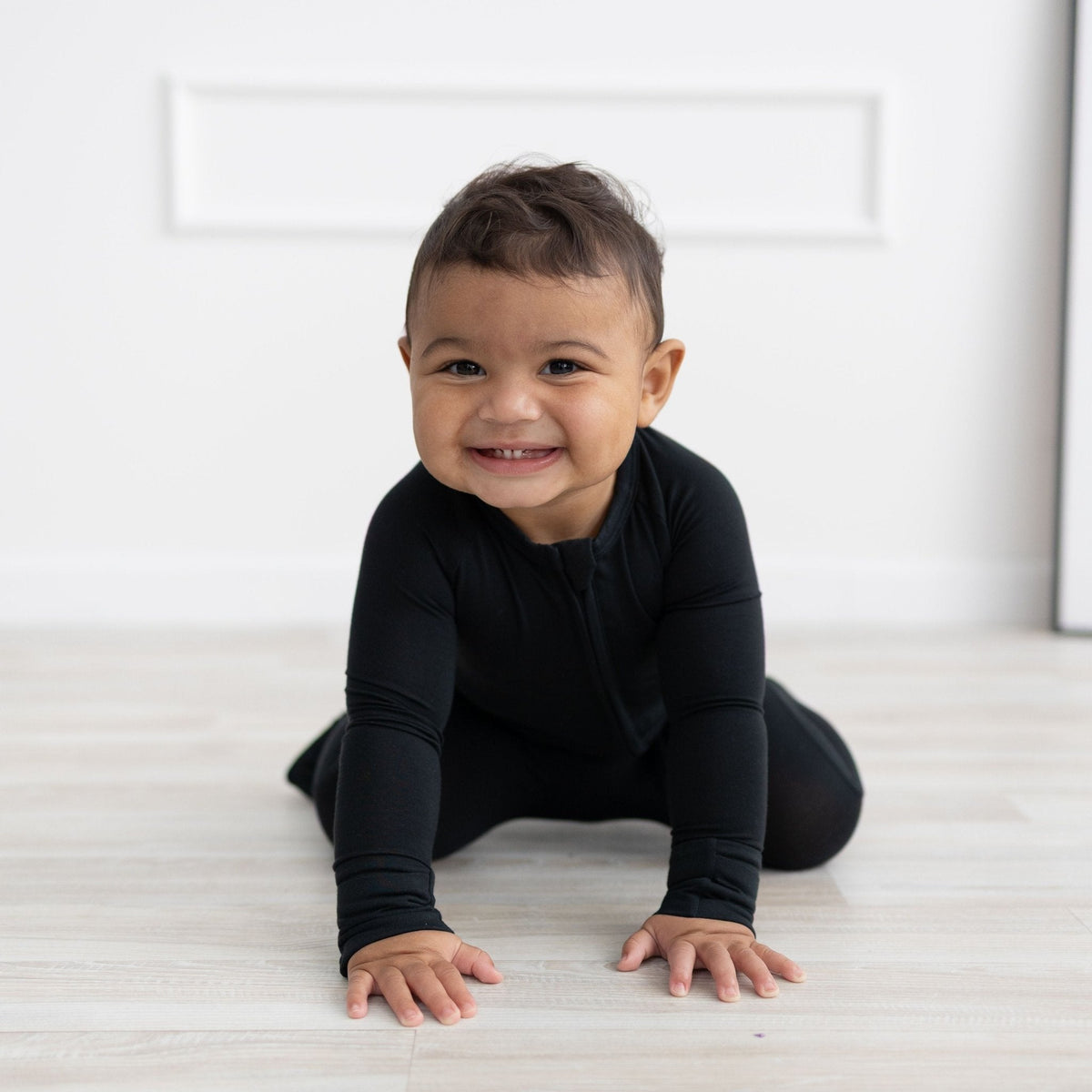 Solid black baby romper with long sleeves, fold-over feet, and a full-length front zipper.
