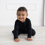 Solid black baby romper with long sleeves, fold-over feet, and a full-length front zipper.