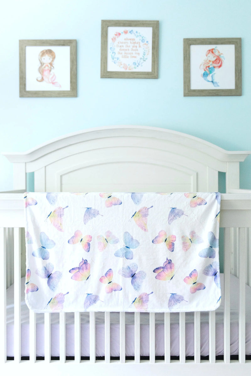 Butterfly-themed baby and toddler blanket on a crib, showcasing vibrant colors and soft texture.
