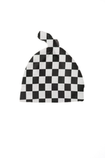 Close-up of a soft organic black and white checkered knotted baby hat by Little Mae & Co on a white background.