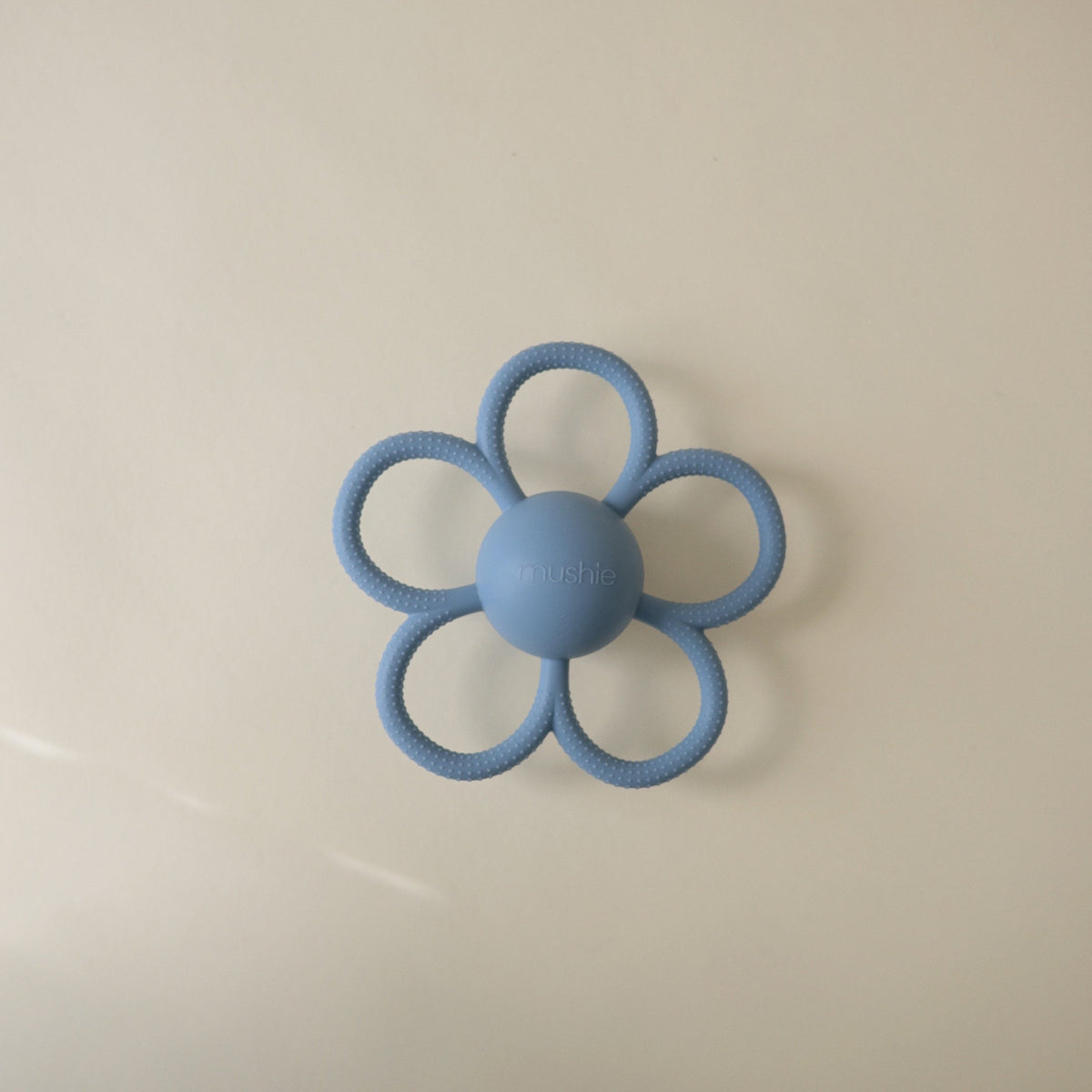 Mushie Daisy Rattle Teether, a white floral baby rattle and teether.
