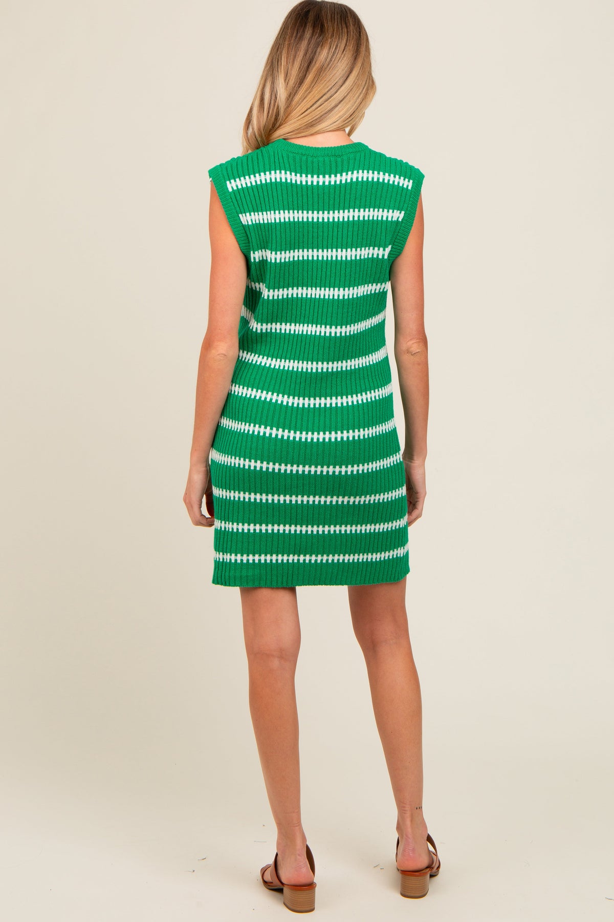 Model wearing a green striped sweater knit sleeveless maternity dress, standing gracefully.