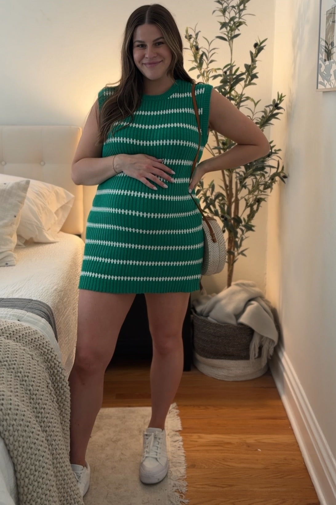 Model wearing a green striped sweater knit sleeveless maternity dress, standing gracefully.