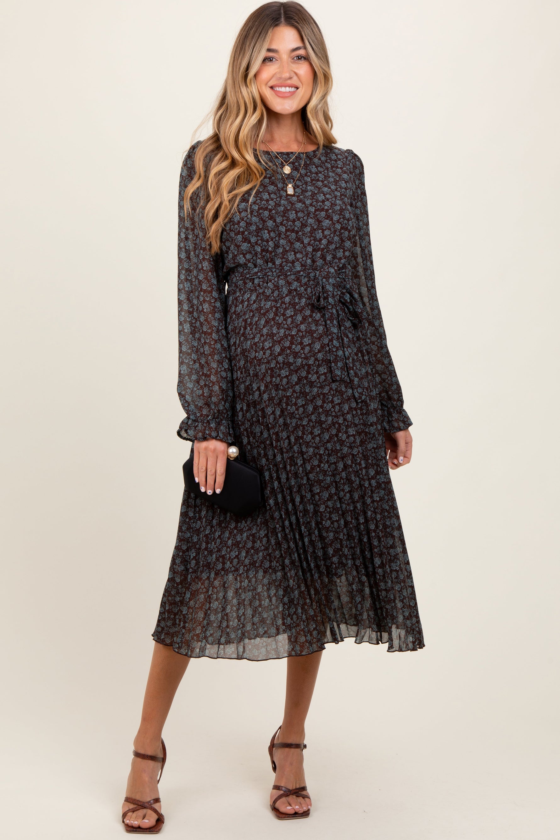 Maternity midi dress with brown floral print, pleated skirt, front tie detail, and long semi-sheer sleeves