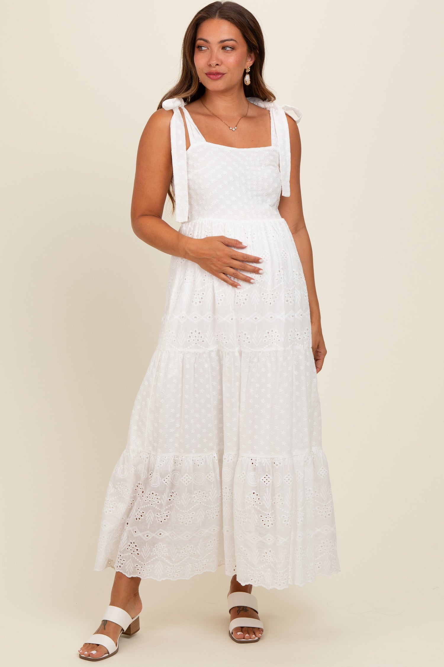 White embroidered eyelet lace maternity maxi dress with tie straps, empire waist, and tiered flowing skirt