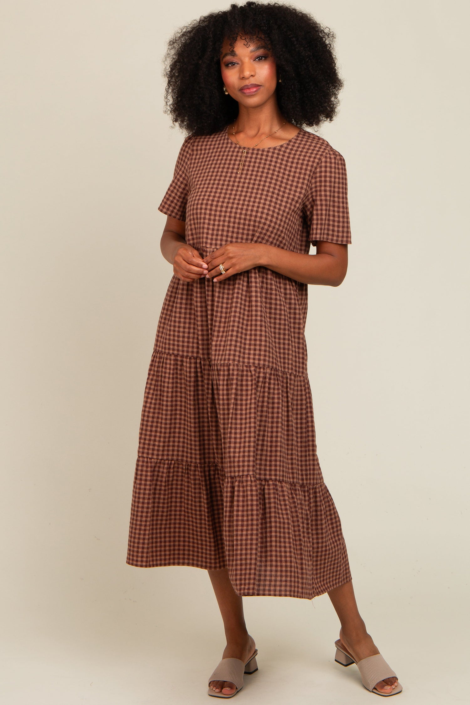 Mocha gingham tiered midi dress with short sleeves and round neckline, styled with sandals.