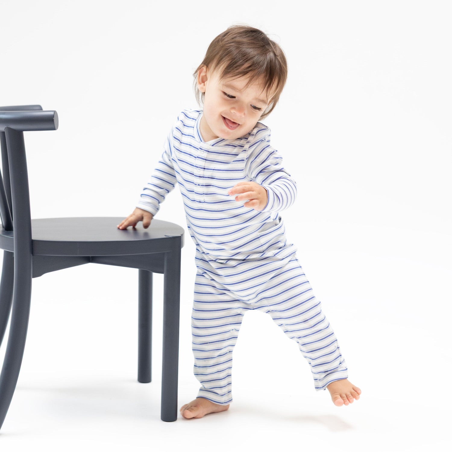 Baby romper in blue vintage stripe with a Henley neckline, buttons at the chest, and snap closures.