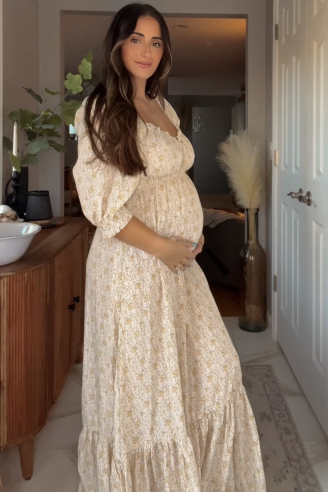 Cream floral maternity maxi dress with sweetheart neckline, empire waist, and flutter sleeves worn by a pregnant woman.