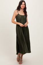 Olive pleated midi dress with spaghetti straps and a tie sash at the waist, styled with heels.