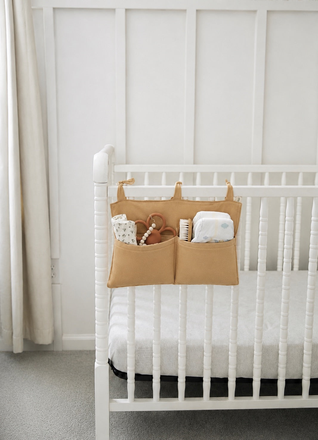 Solid brown cotton crib organizer with two deep pockets and fabric straps for hanging on a crib rail