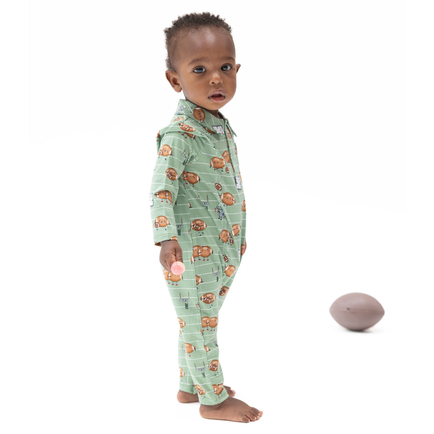 Convertible baby romper with an allover print of footballs playing football, featuring a full-length front zipper and covered
