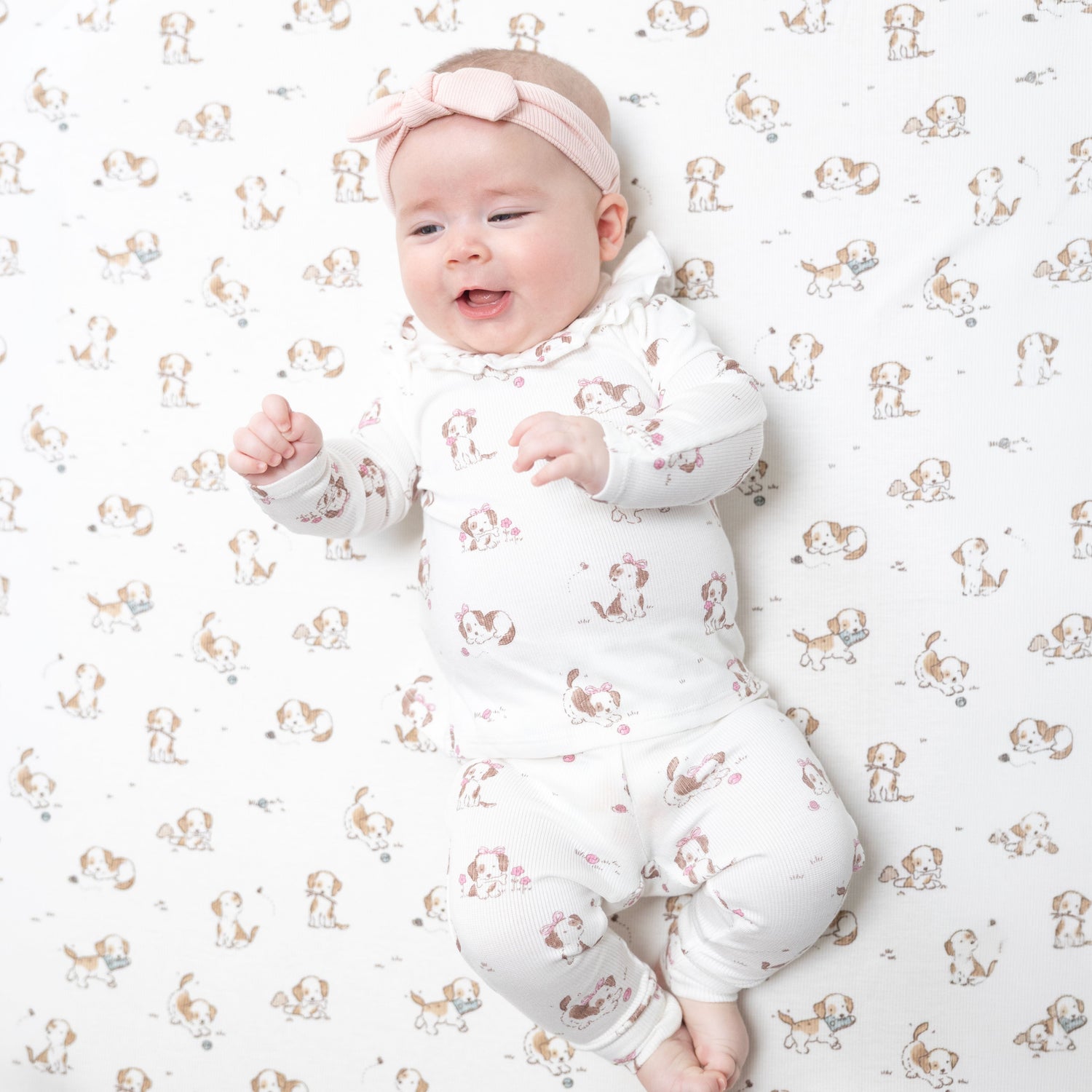 Two-piece baby set in pink with a puppy print, long-sleeve ruffle-collar top and matching elastic-waist pants.