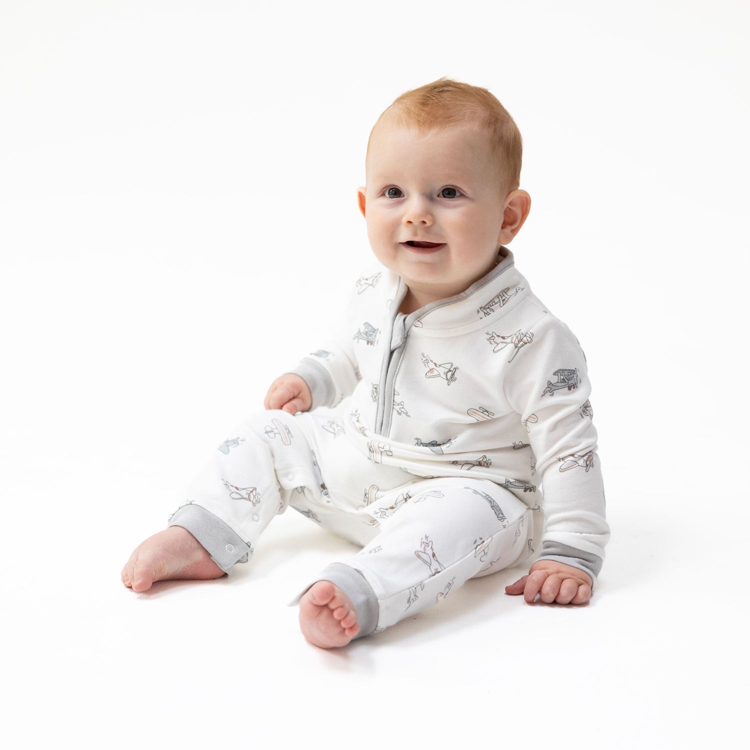 One-piece baby romper in organic French terry with a vintage airplane and pilot print, zip neck front, and ribbed cuffs.