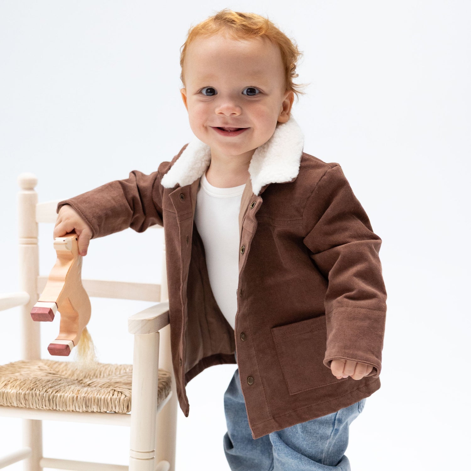 Baby corduroy jacket in beaver-brown with a plush sherpa collar, brass cap snaps, and two front pockets.