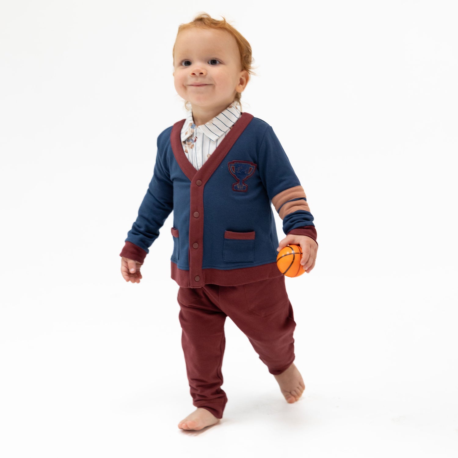 Snap-front baby cardigan in French terry with a trophy applique, striped sleeves, and two front pockets.
