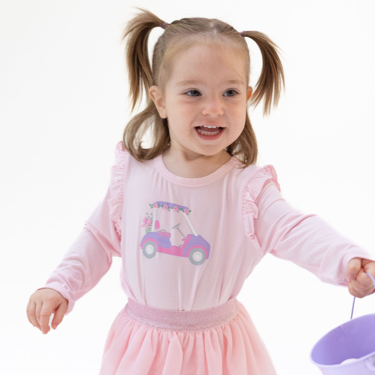 Long sleeve tee with shoulder ruffles and a pink golf cart with flowers puff-print on the front.