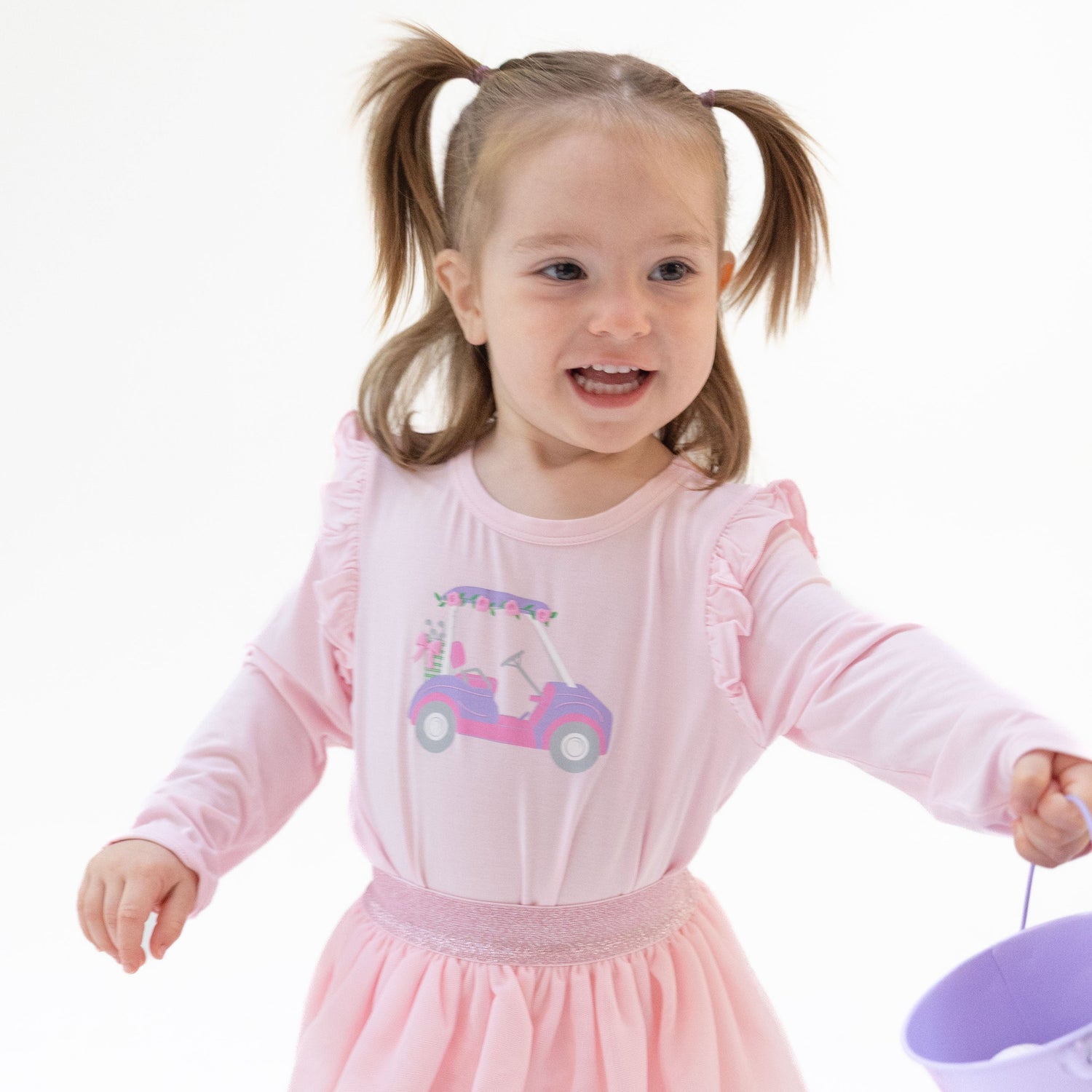 Long sleeve tee with shoulder ruffles and a pink golf cart with flowers puff-print on the front.