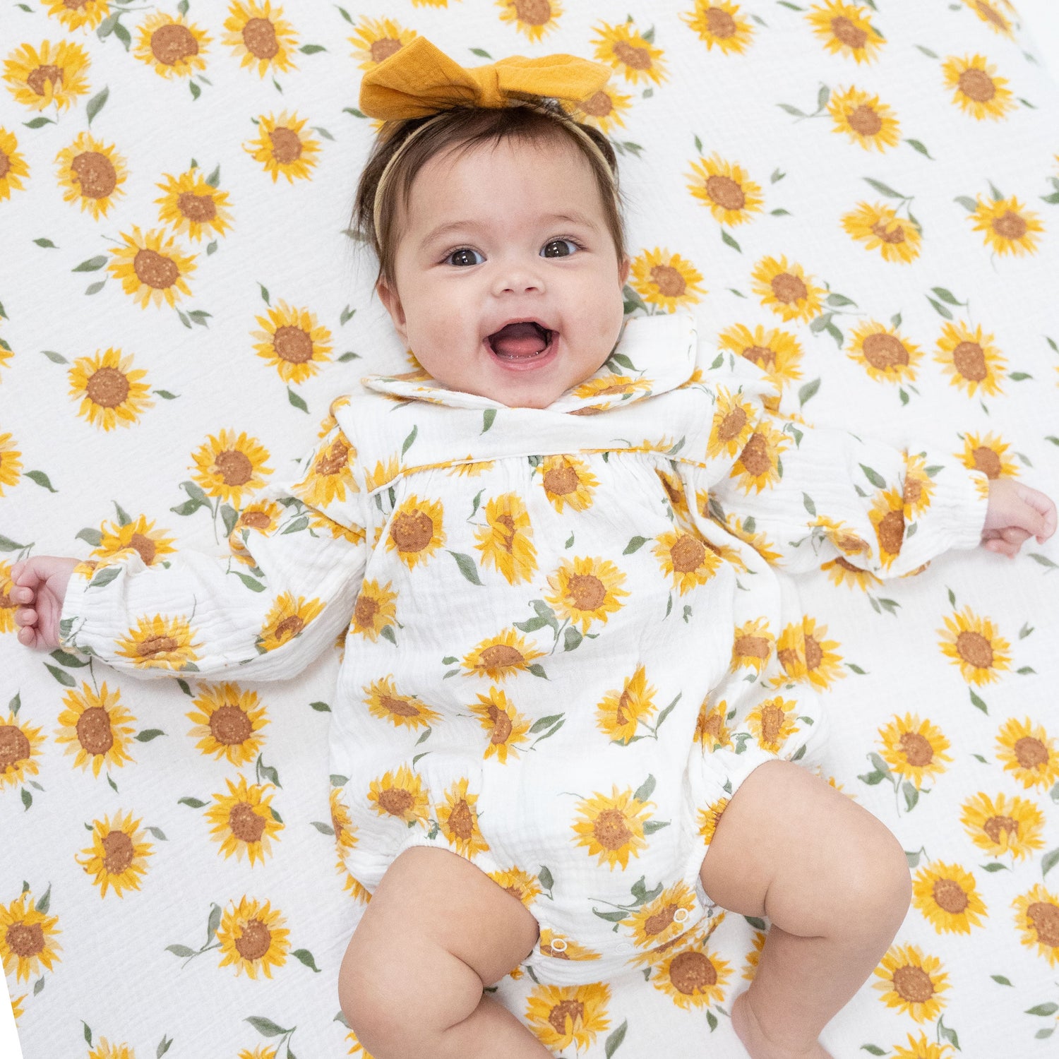 Baby bubble romper in sunflower print with Peter Pan collar, piping trim, and elastic-gathered wrists.