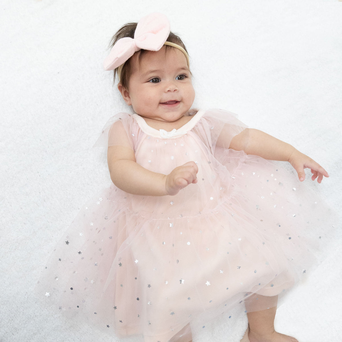 Soft pink velour baby dress with silver foil star tulle overlay, flutter sleeves and keyhole back opening