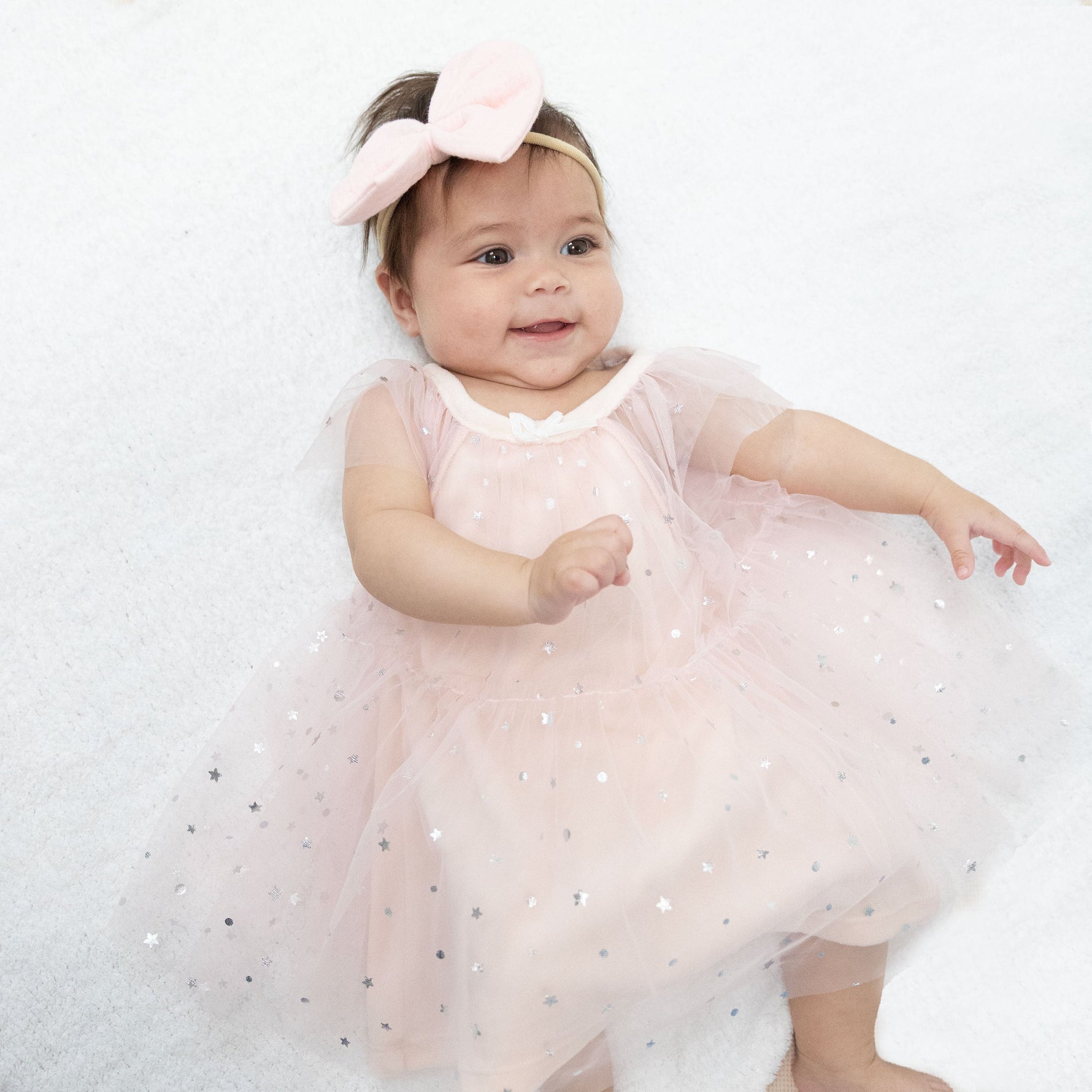 Soft pink velour baby dress with silver foil star tulle overlay, flutter sleeves and keyhole back opening