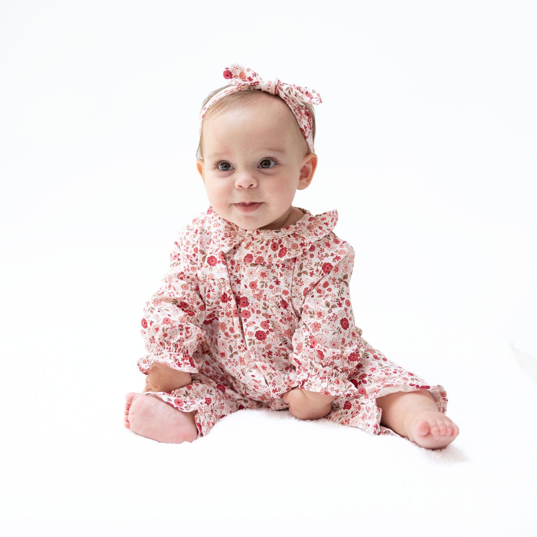 Long sleeve baby romper in a serene floral print with a ruffle collar and snap leg closures