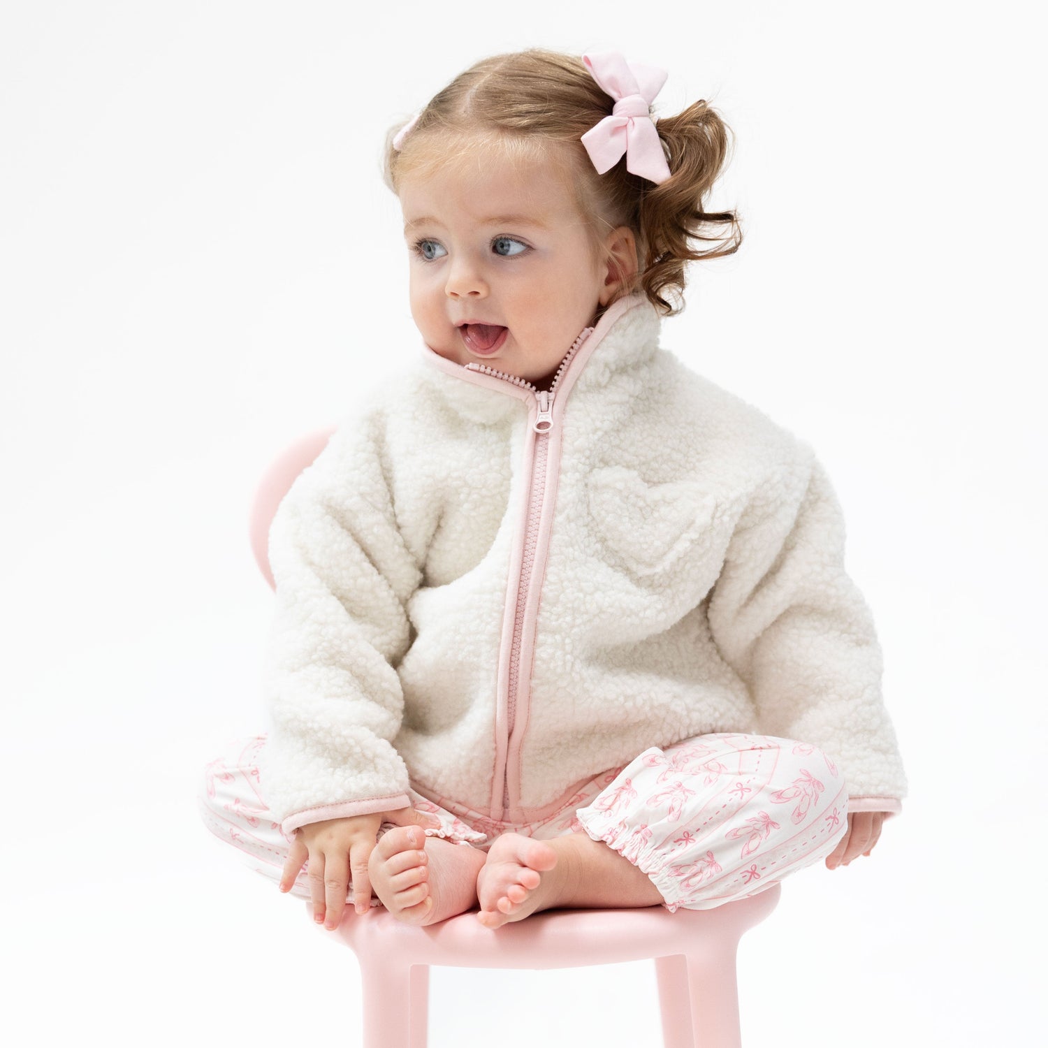 Pink sherpa zip-front baby jacket with a heart-shaped chest pocket and bound edges.