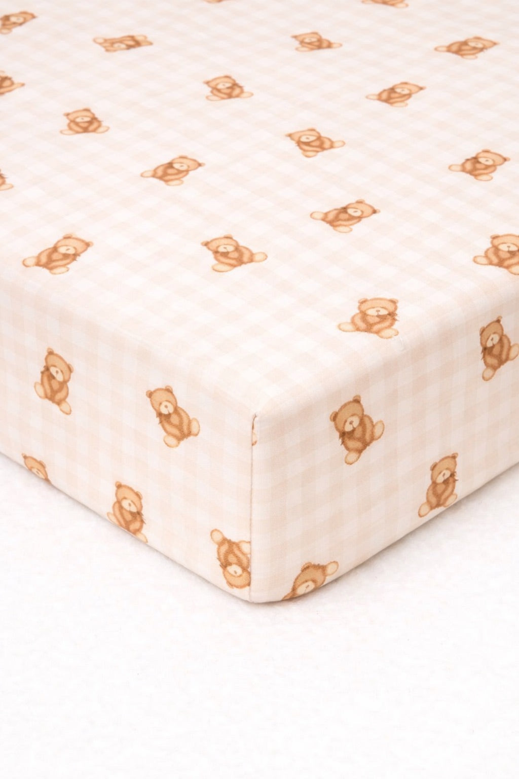 Beige and white gingham crib sheet fitted on a standard crib mattress.
