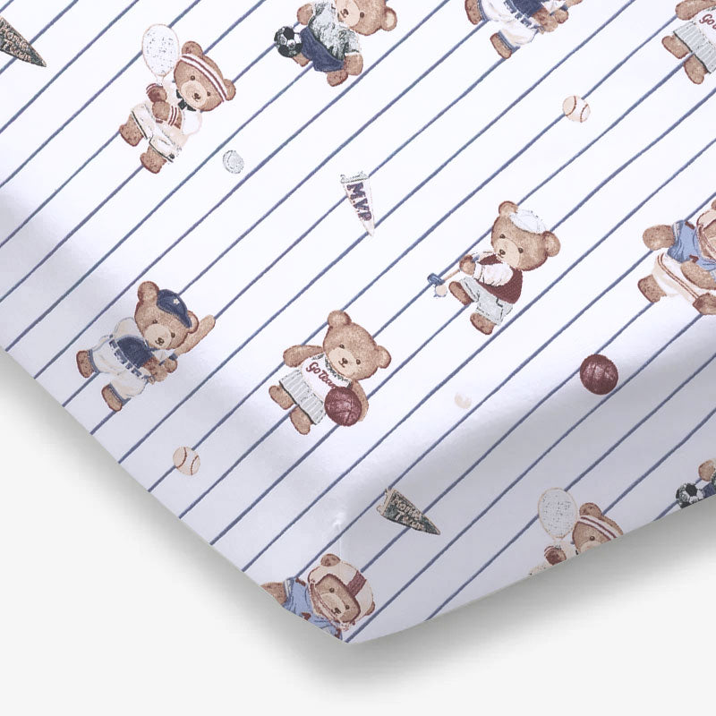 Crib sheet with a mixed sports bears print in soft muted tones on a fitted crib mattress