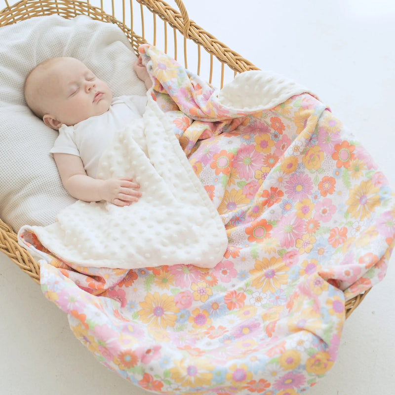 Baby sleeping with retro floral minky blanket in a wicker basket.