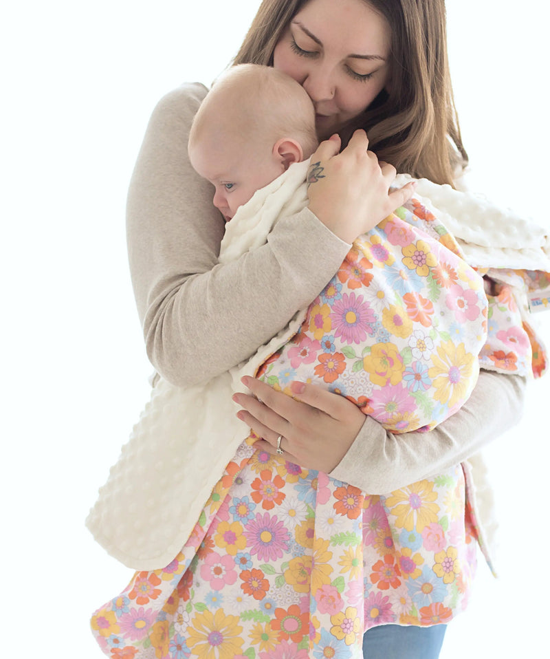 Baby wrapped in retro floral minky blanket being held by adult.