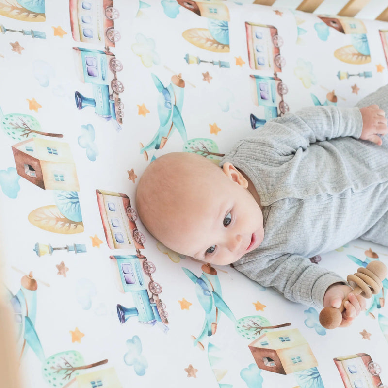 Fitted crib sheet with airplane and train pattern, soft fabric, perfect for photos.