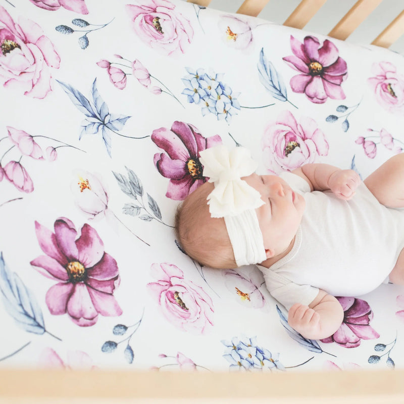 Vintage floral fitted crib sheet in crib with baby lying on it.
