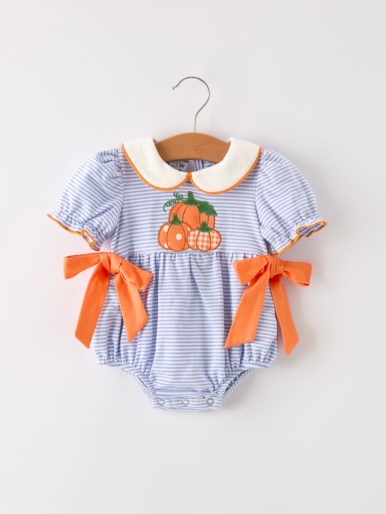 Girls romper with striped lapel collar and a pumpkin applique bow on the front, styled for fall.