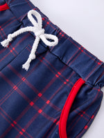 Young boy wearing a red apple graphic t-shirt and blue plaid shorts, smiling, ready for school.