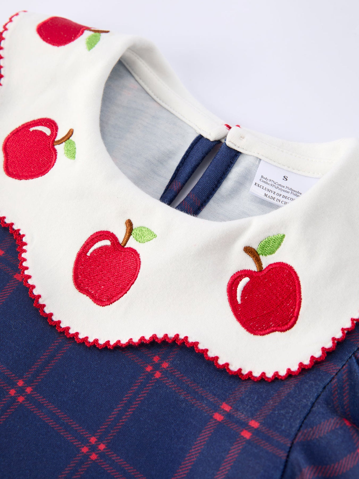 Girl wearing an organic apple plaid dress with scallop hem and bow, perfect for back to school.