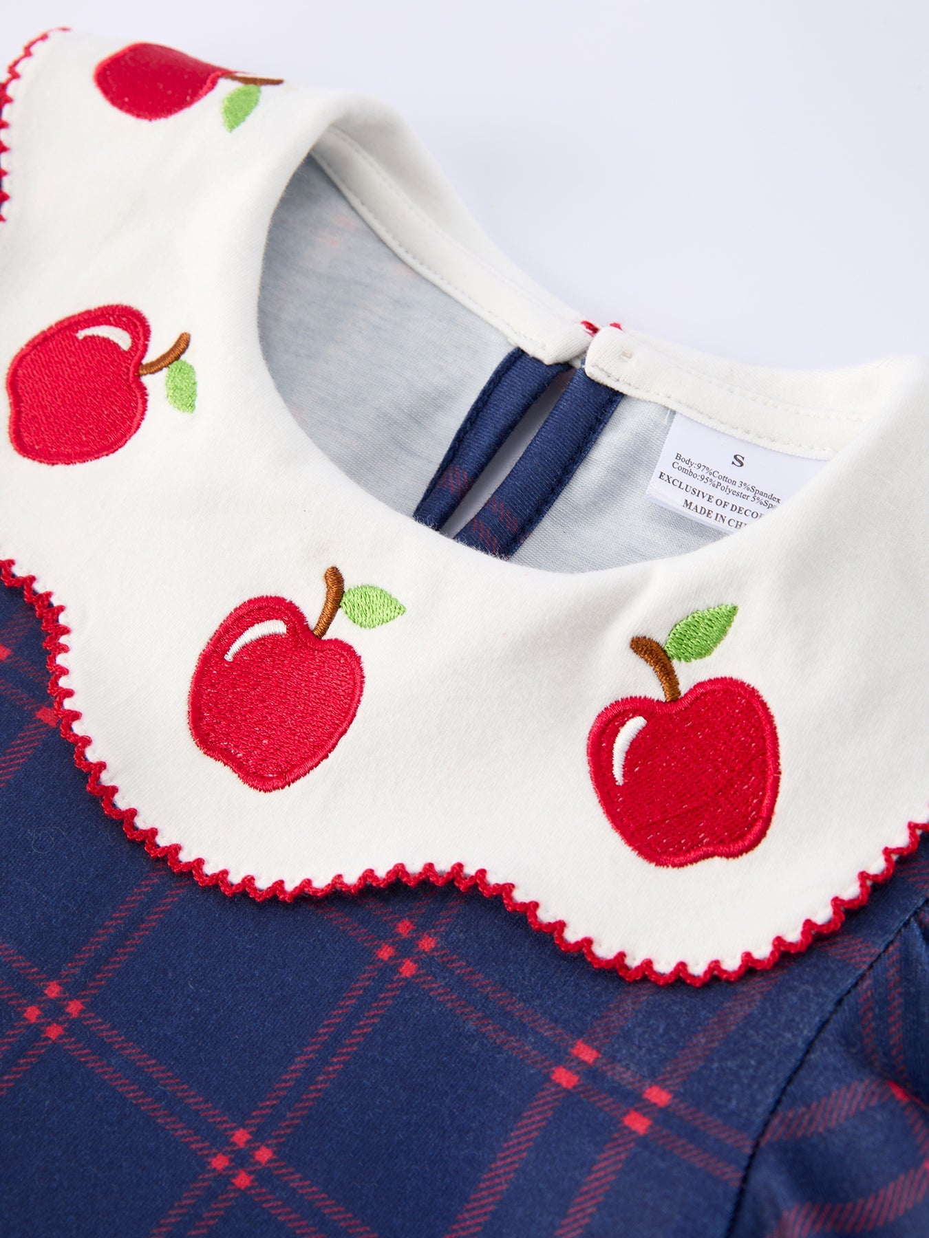 Girl wearing an organic apple plaid dress with scallop hem and bow, perfect for back to school.