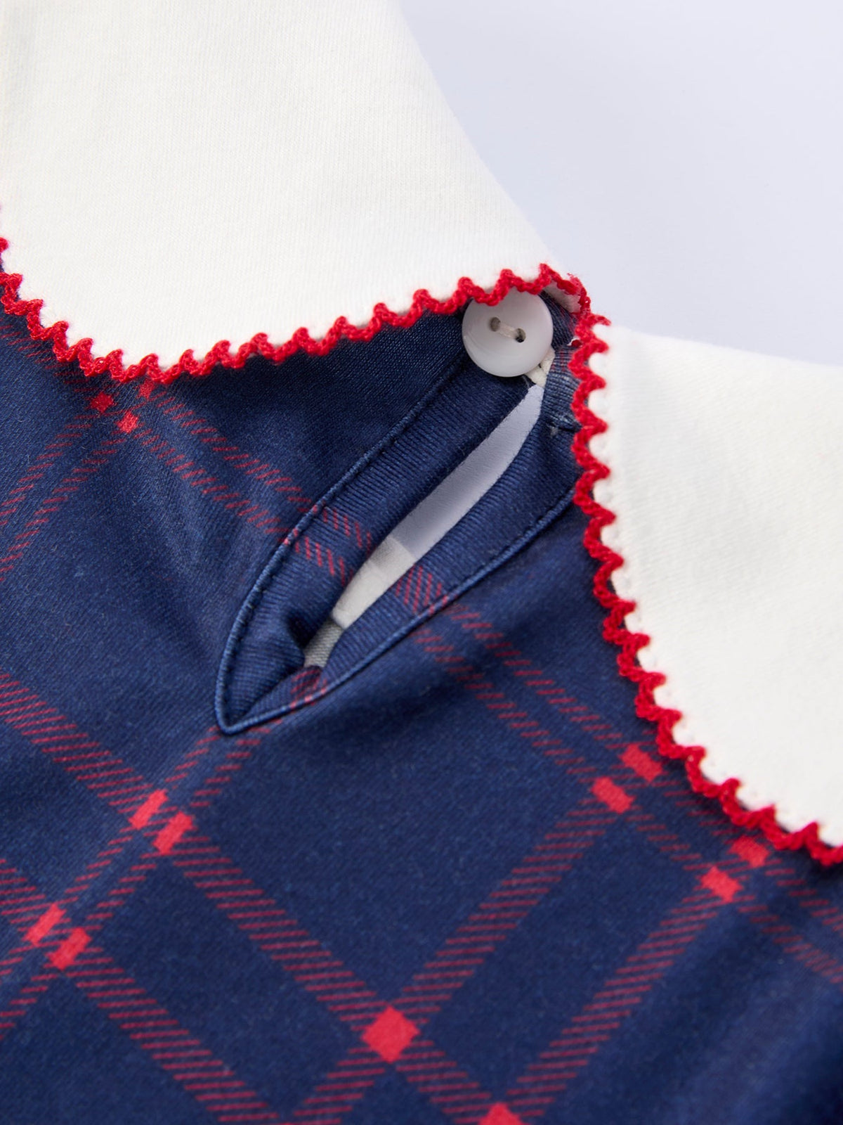 Girl wearing an organic apple plaid dress with scallop hem and bow, perfect for back to school.