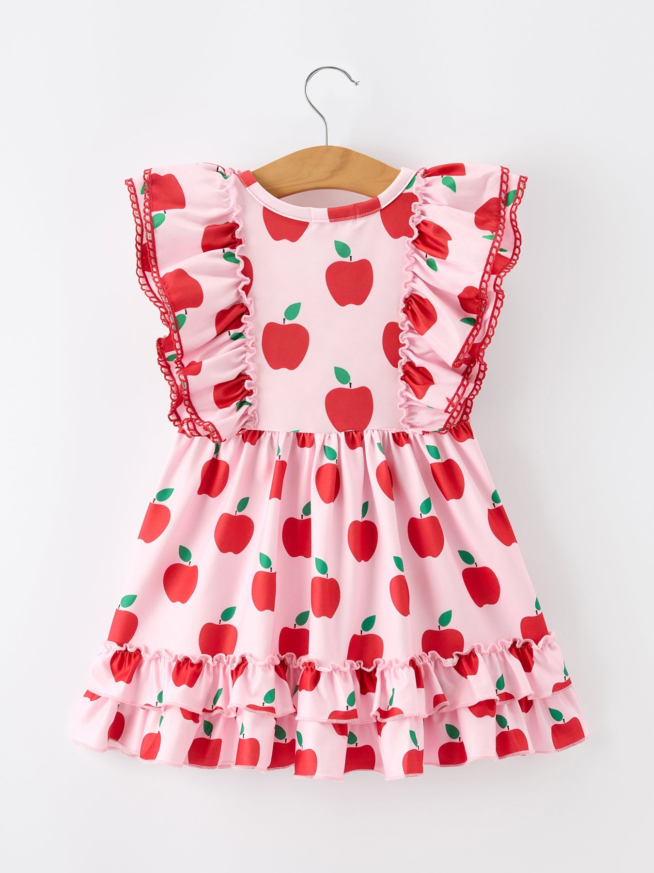 Girl wearing Rylee Faith Designs apple print twirl dress with flutter sleeves, playing happily.