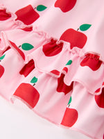 Girl wearing Rylee Faith Designs apple print twirl dress with flutter sleeves, playing happily.