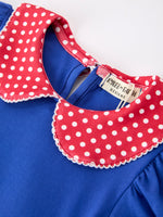 Young girl wearing a Rylee Faith apple polka dot dress with a petal collar and bow detail, perfect for back to school.