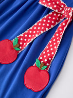 Young girl wearing a Rylee Faith apple polka dot dress with a petal collar and bow detail, perfect for back to school.