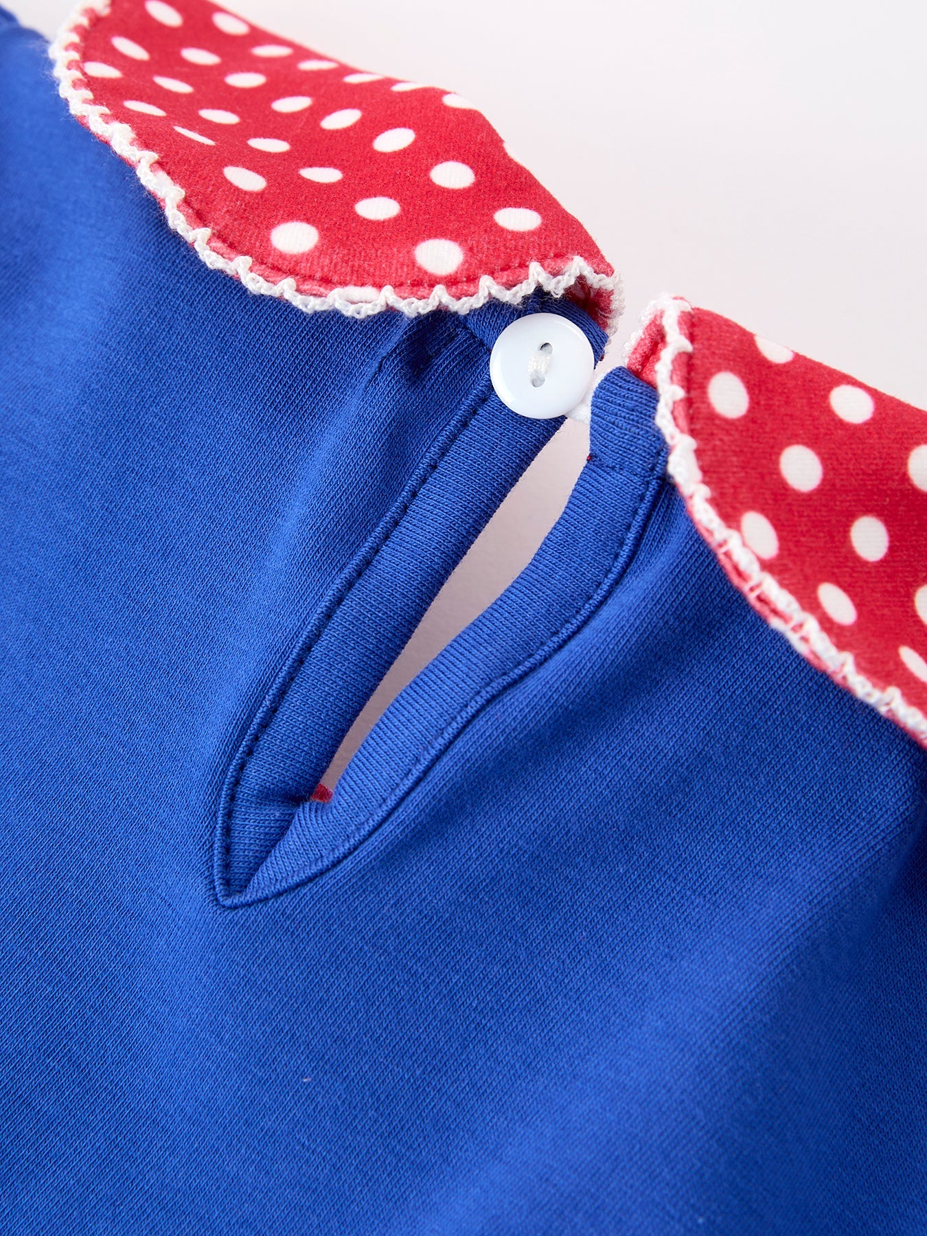 Young girl wearing a Rylee Faith apple polka dot dress with a petal collar and bow detail, perfect for back to school.