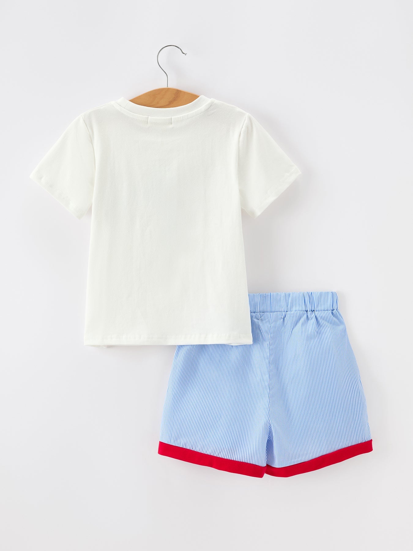 Boy wearing a white short-sleeve top with apple pencil embroidery and navy blue shorts, perfect for back to school.