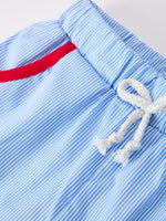 Boy wearing a white short-sleeve top with apple pencil embroidery and navy blue shorts, perfect for back to school.