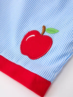 Boy wearing a white short-sleeve top with apple pencil embroidery and navy blue shorts, perfect for back to school.
