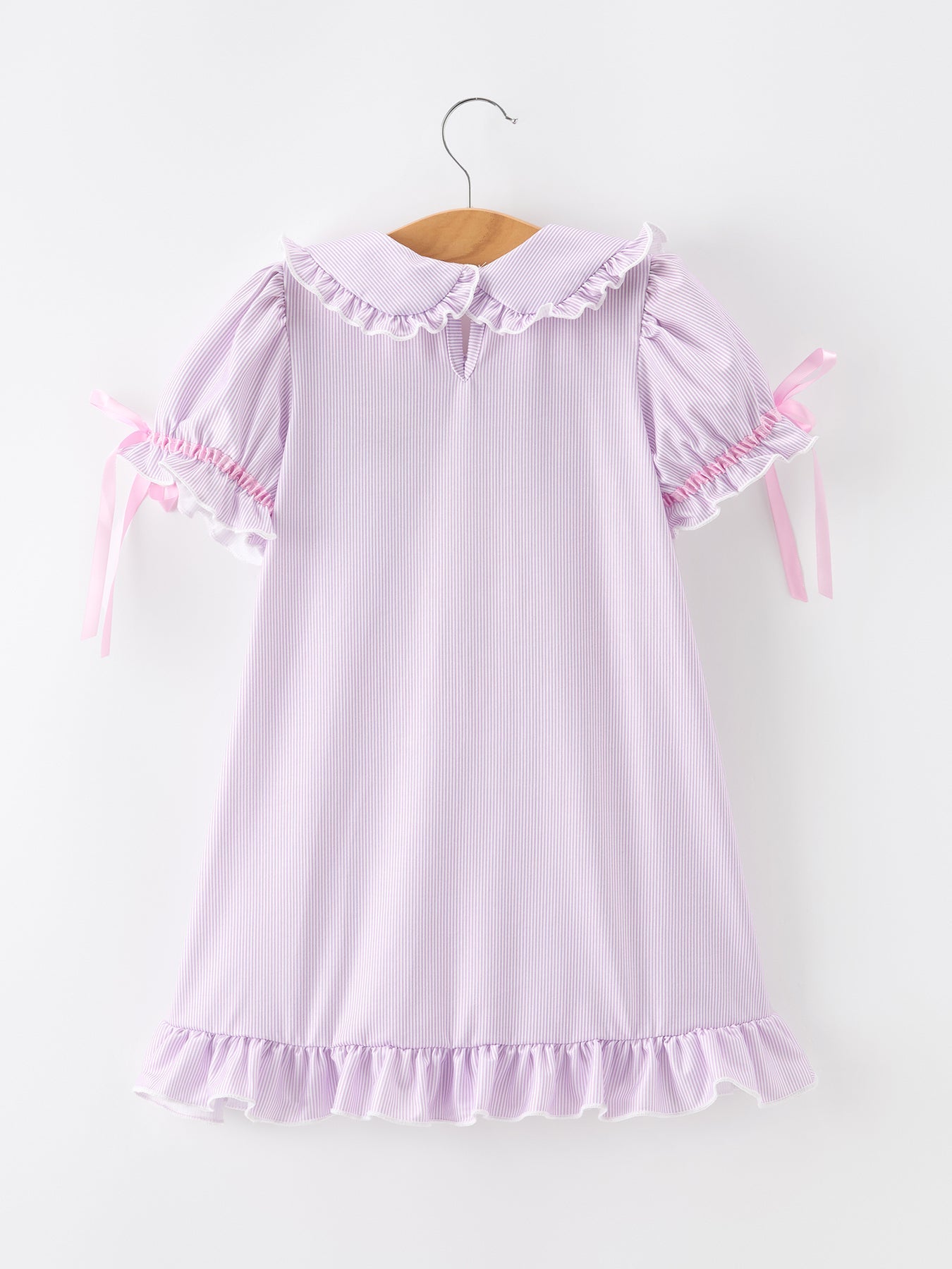 Young girl wearing a purple dress with a pencil applique, petals collar, and ruffled hem.