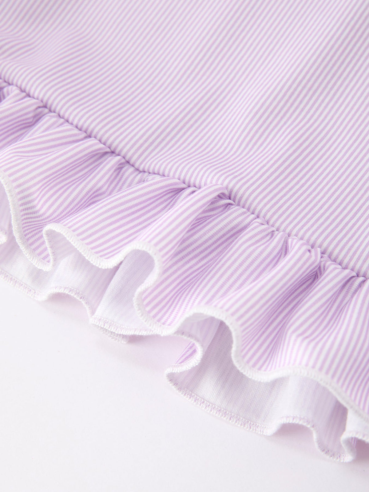 Young girl wearing a purple dress with a pencil applique, petals collar, and ruffled hem.