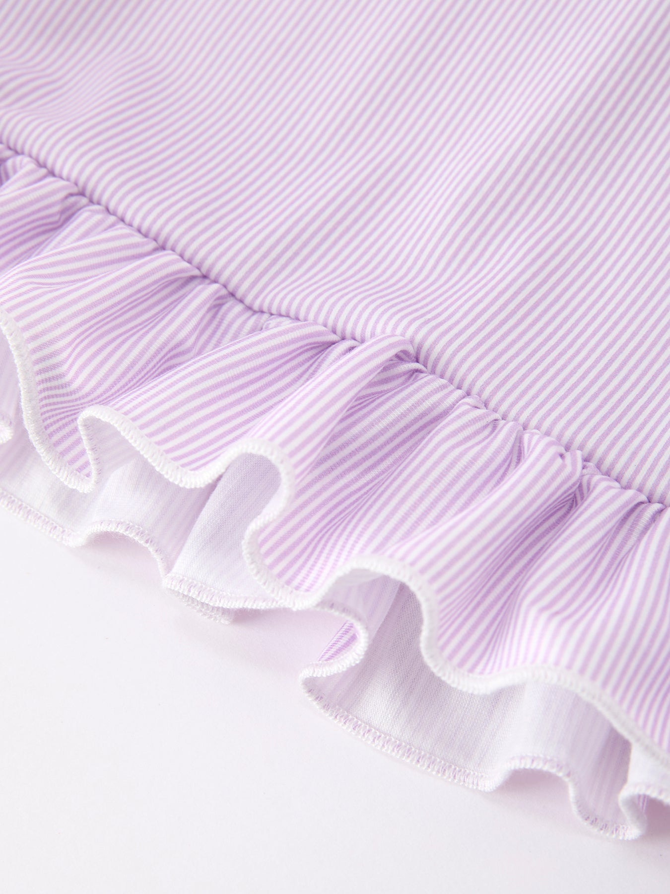 Young girl wearing a purple dress with a pencil applique, petals collar, and ruffled hem.