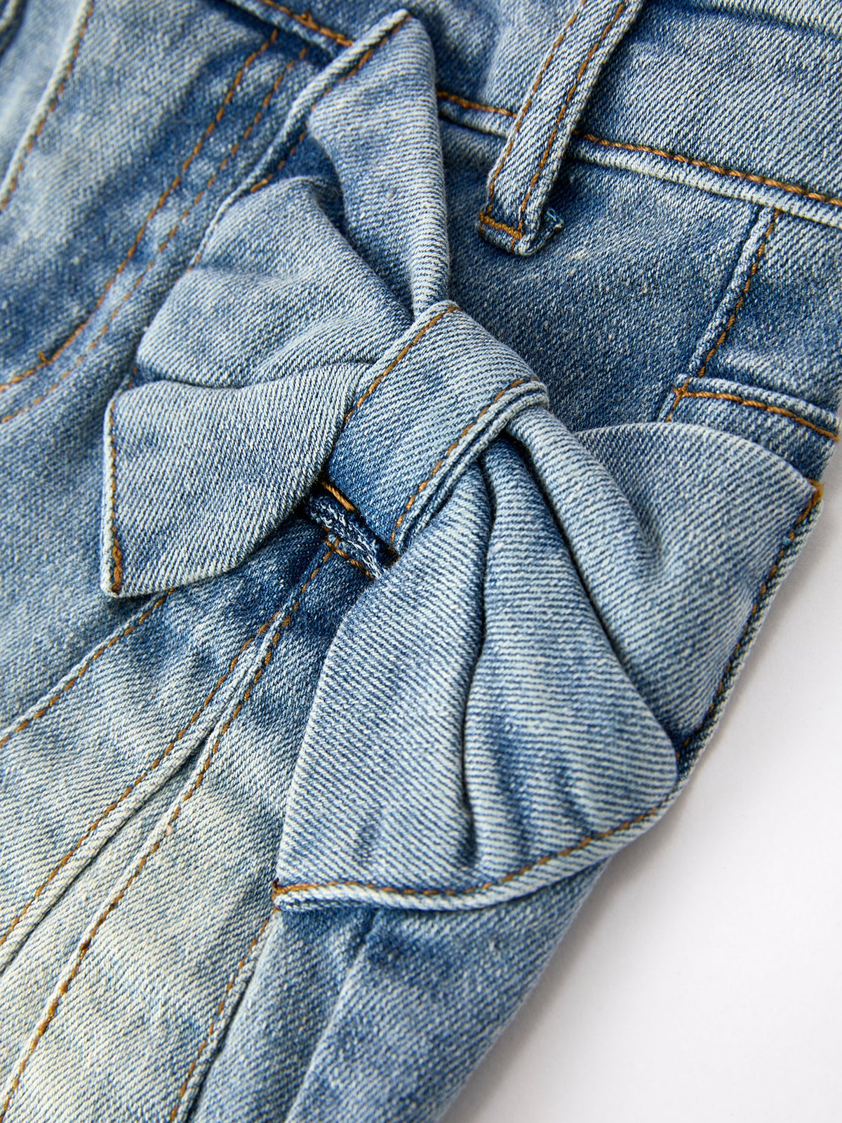 Toddler girl wearing Rylee Faith Designs denim bow skirt with cute side bow details, smiling.
