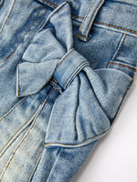 Toddler girl wearing Rylee Faith Designs denim bow skirt with cute side bow details, smiling.